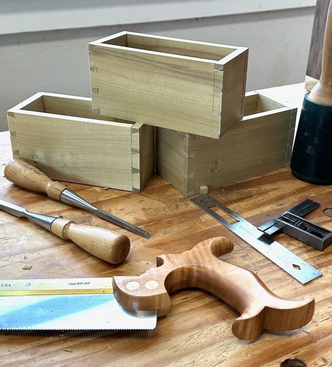 Dovetailed boxes and hand tools on a woodworking bench